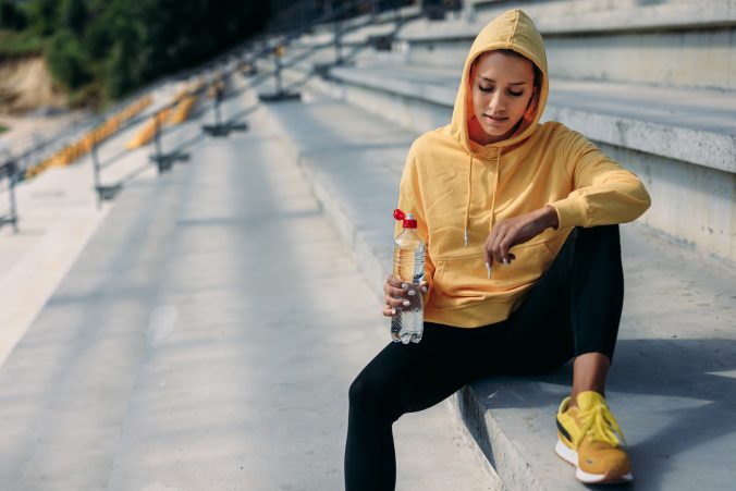 Female athlete in yellow hoodie relaxing on steps