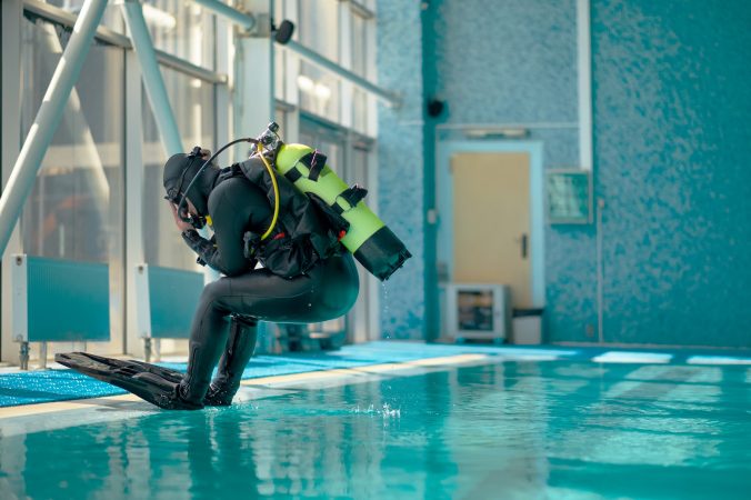 Male diver in scuba gear jumps into the pool