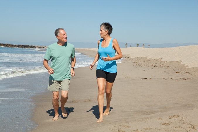 Senior couple jogging on beach